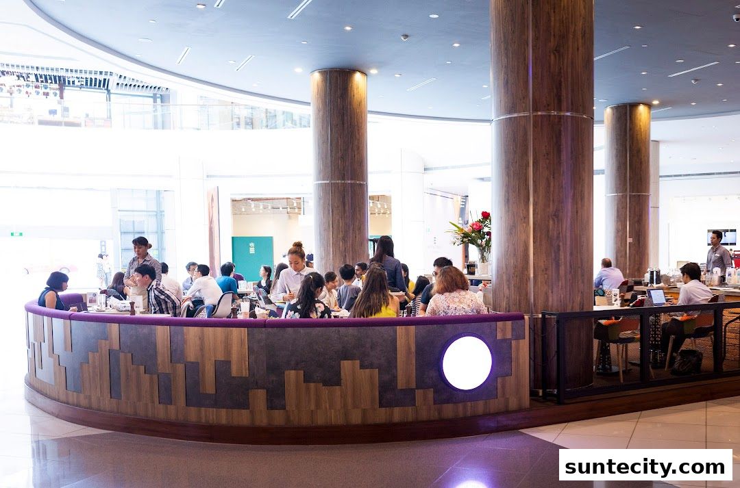 People dining and working at a modern cafe with large wooden pillars and bright lighting.