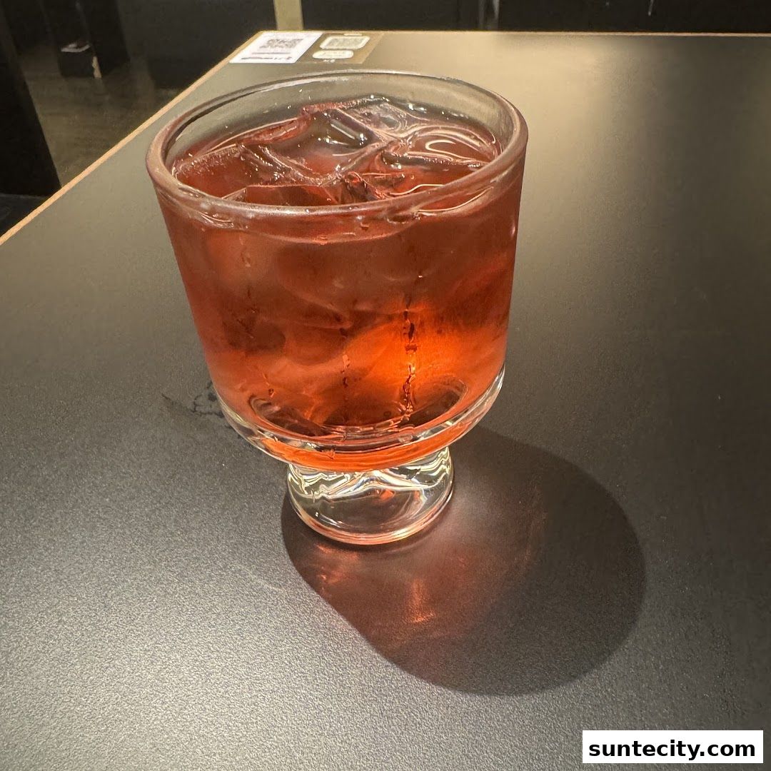 A refreshing red beverage with ice in a glass on a dark table.