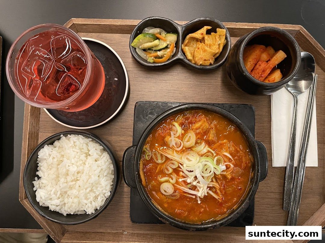 A Korean meal set with kimchi stew, rice, side dishes, and a drink.