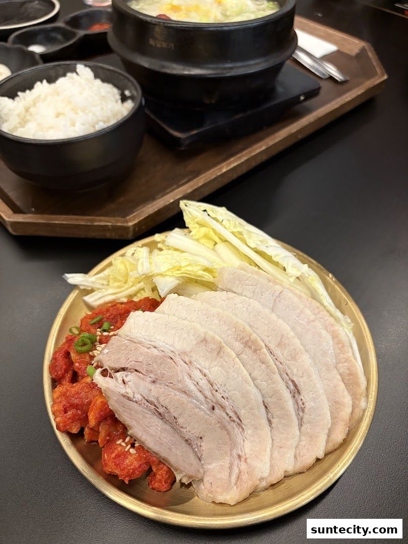 A close-up of a Korean meal featuring sliced pork, kimchi, and a bowl of rice.
