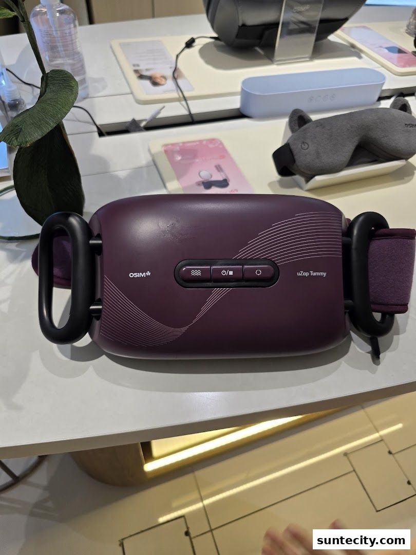 A close-up of an OSIM uZap Tummy massager on display with other wellness products.