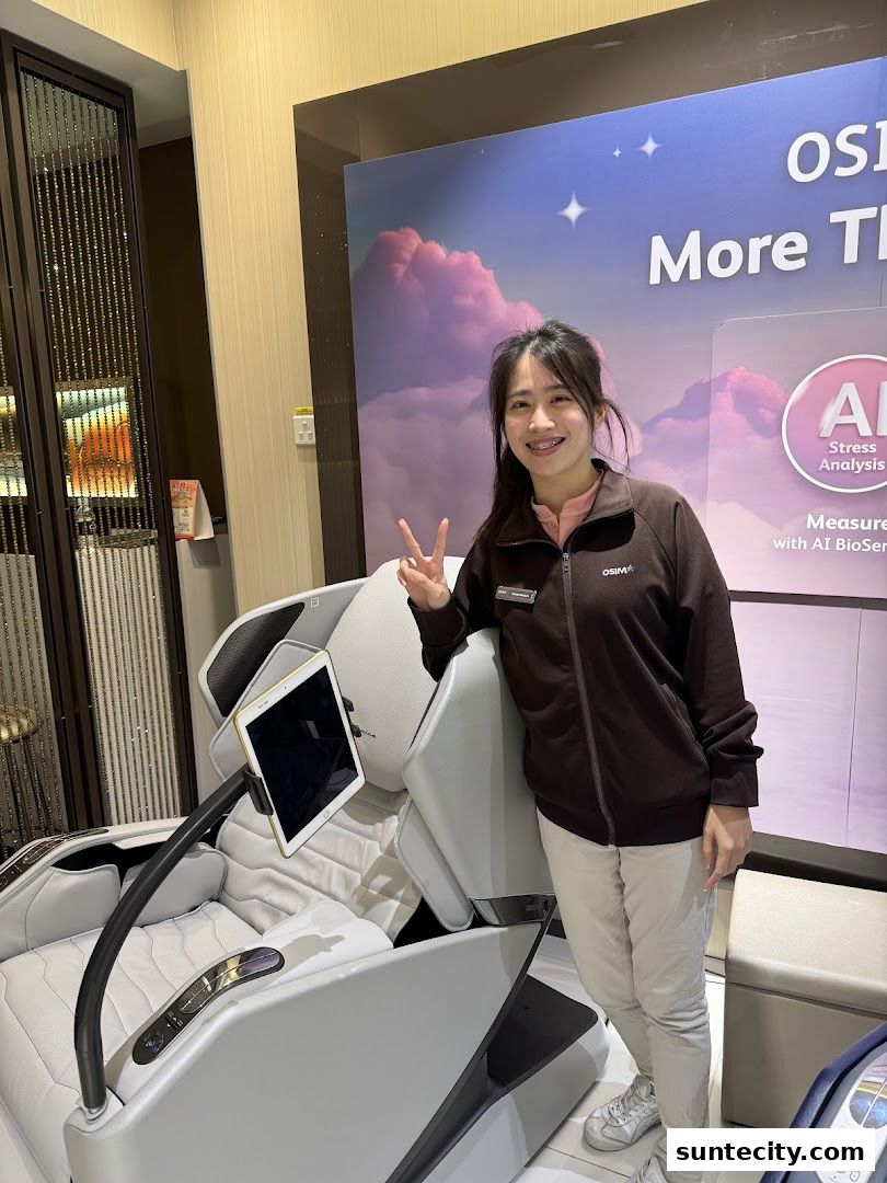 A smiling woman poses with a massage chair and a large promotional banner.