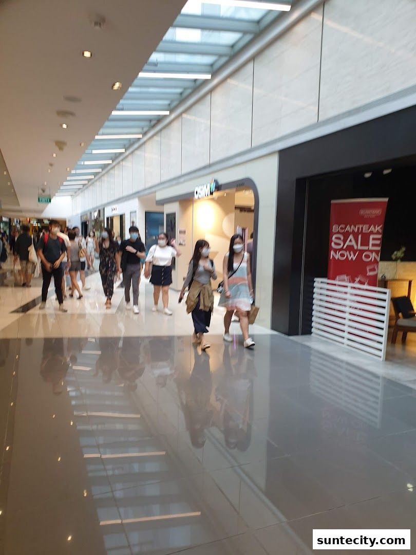 People walking in a mall hallway past the OSIM shop with a sale banner.