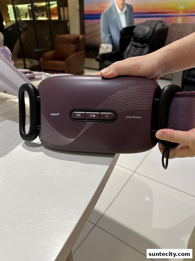 A person holds an OSIM uZap Tummy massager in a retail store setting.