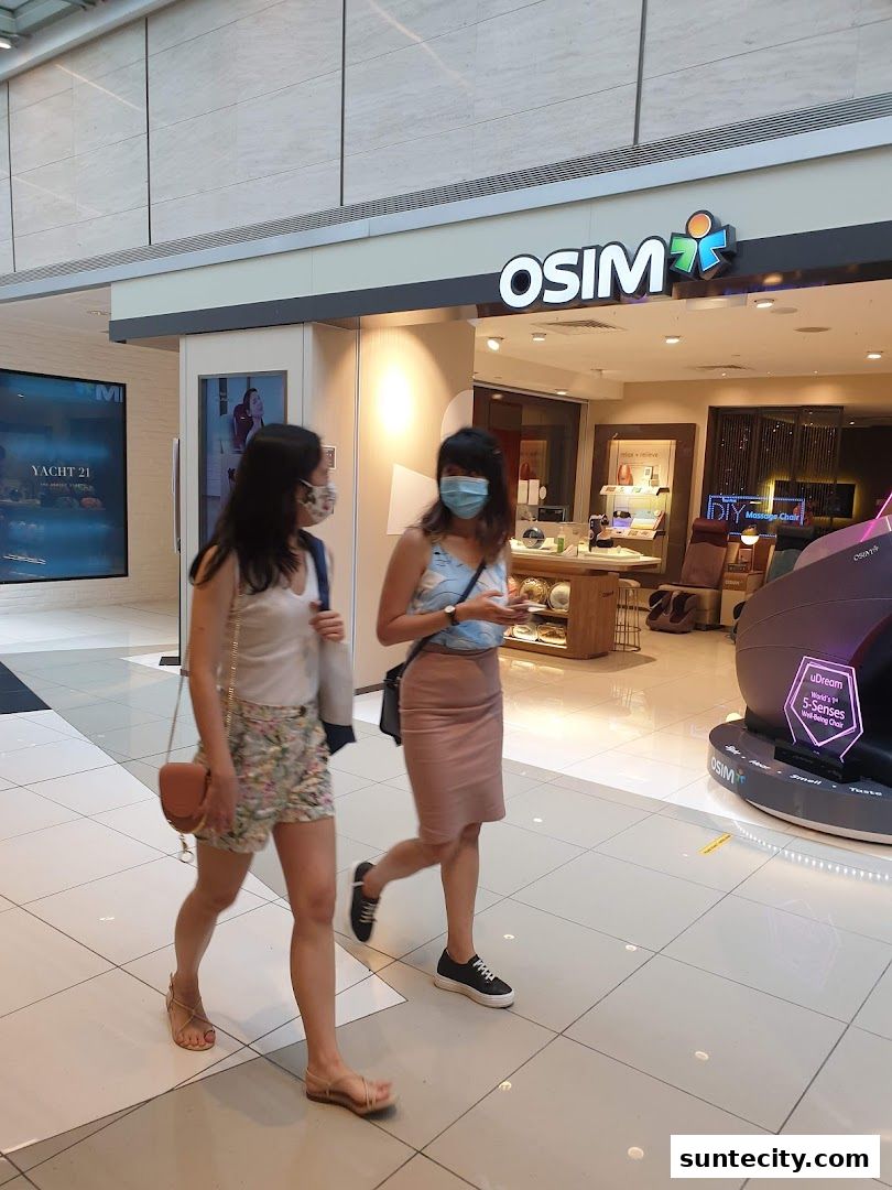 Two women walk past the OSIM store in Suntec City Mall, showcasing massage chairs.