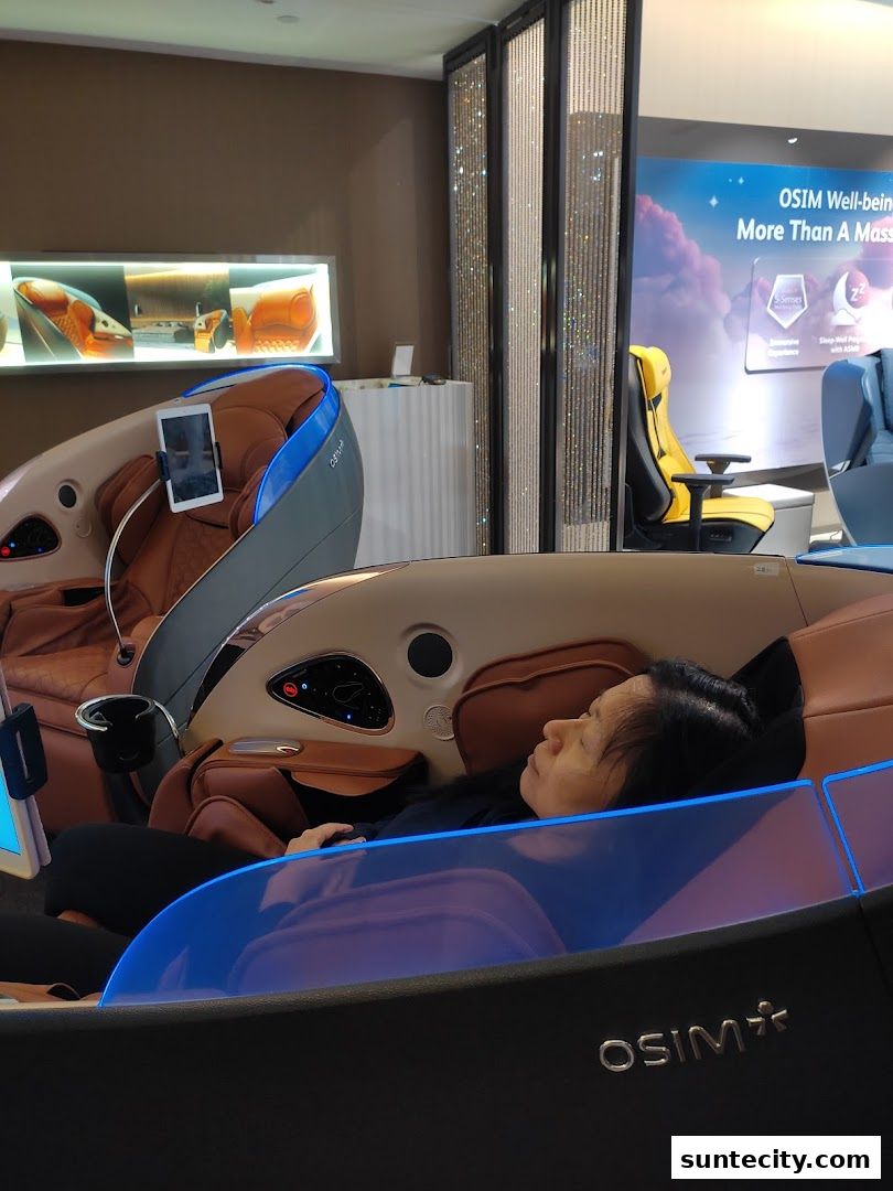A woman relaxing in an OSIM massage chair with a tablet attached.