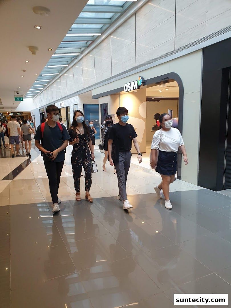 People walking past the OSIM store in a mall, with the shop's entrance clearly visible.