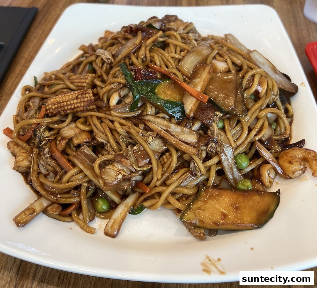 A plate of stir-fried noodles with vegetables and shrimp on a white plate.