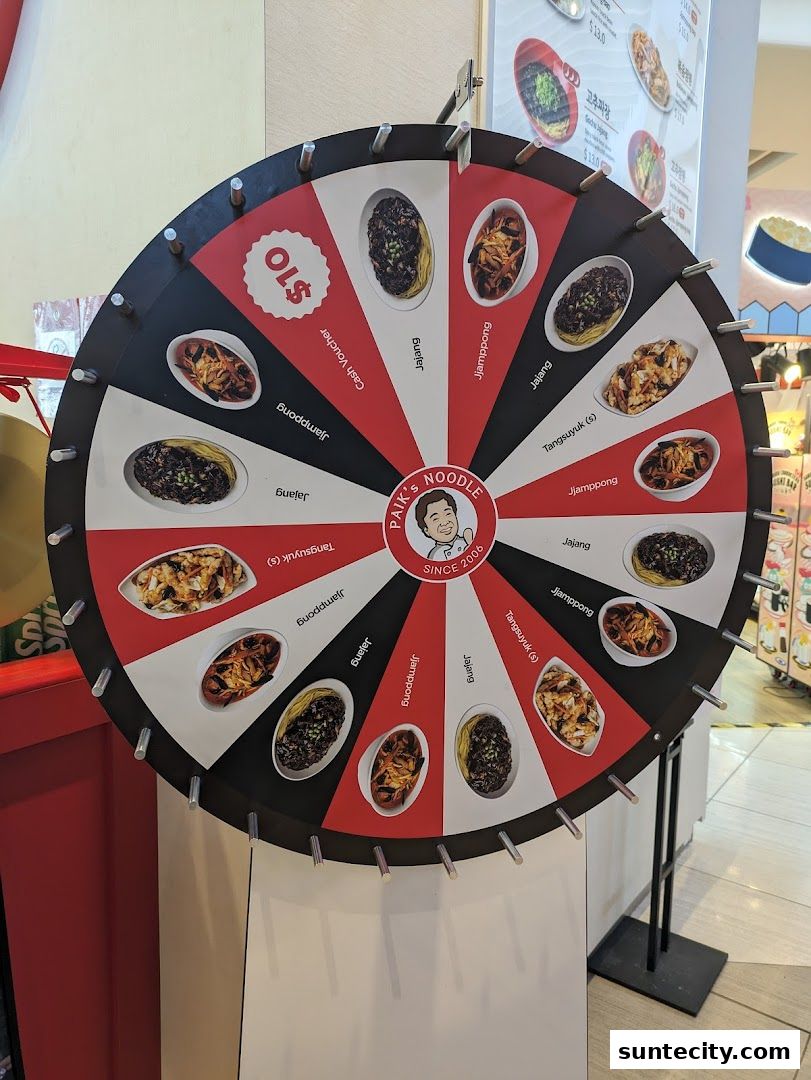 A spinning wheel with food items and a $10 cash voucher prize from Paik's Noodle.