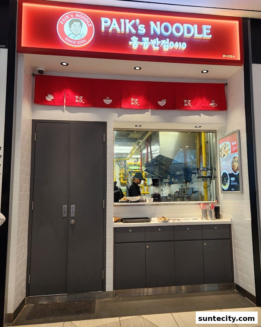 The exterior of Paik's Noodle restaurant with its prominent signage and a glimpse into the kitchen.