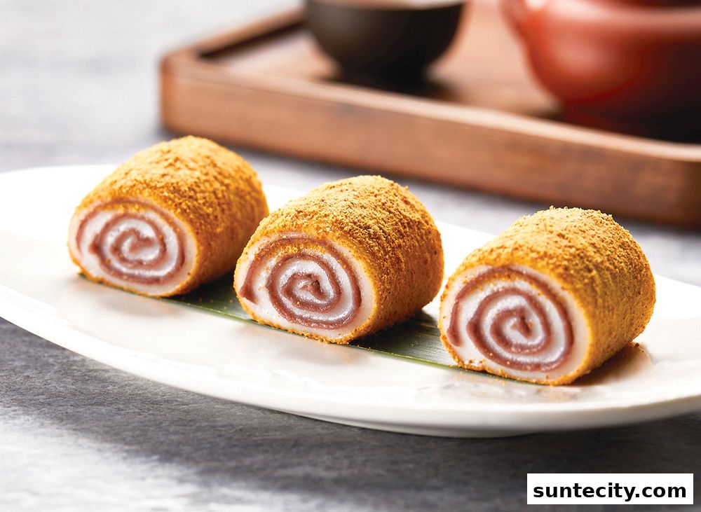 Three sweet red bean paste rolls coated in a golden powder on a white plate.