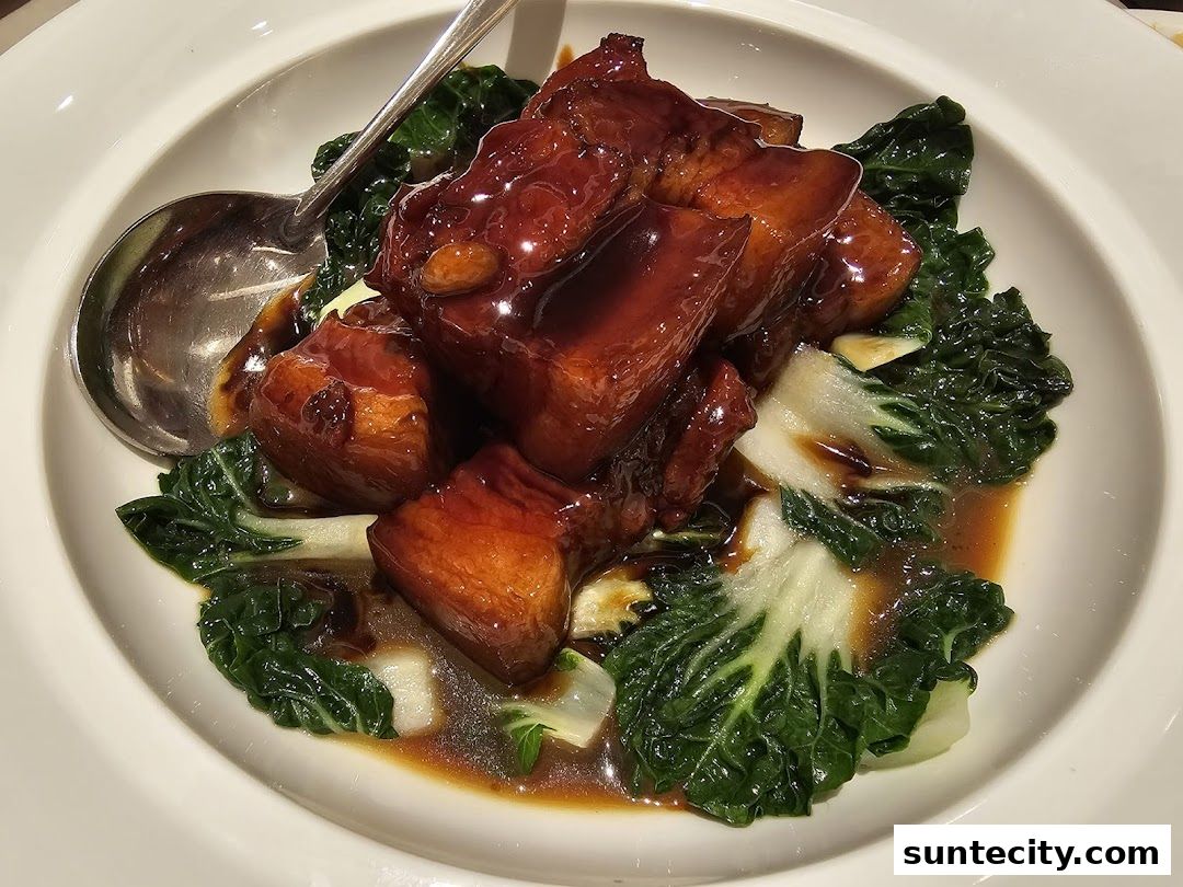 A close-up of braised pork belly with bok choy in a savory sauce.