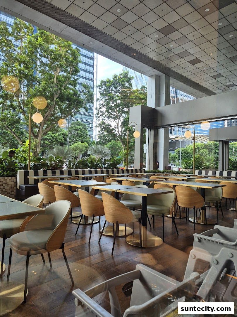 Interior view of a restaurant with tables, chairs, and a view of trees and buildings.