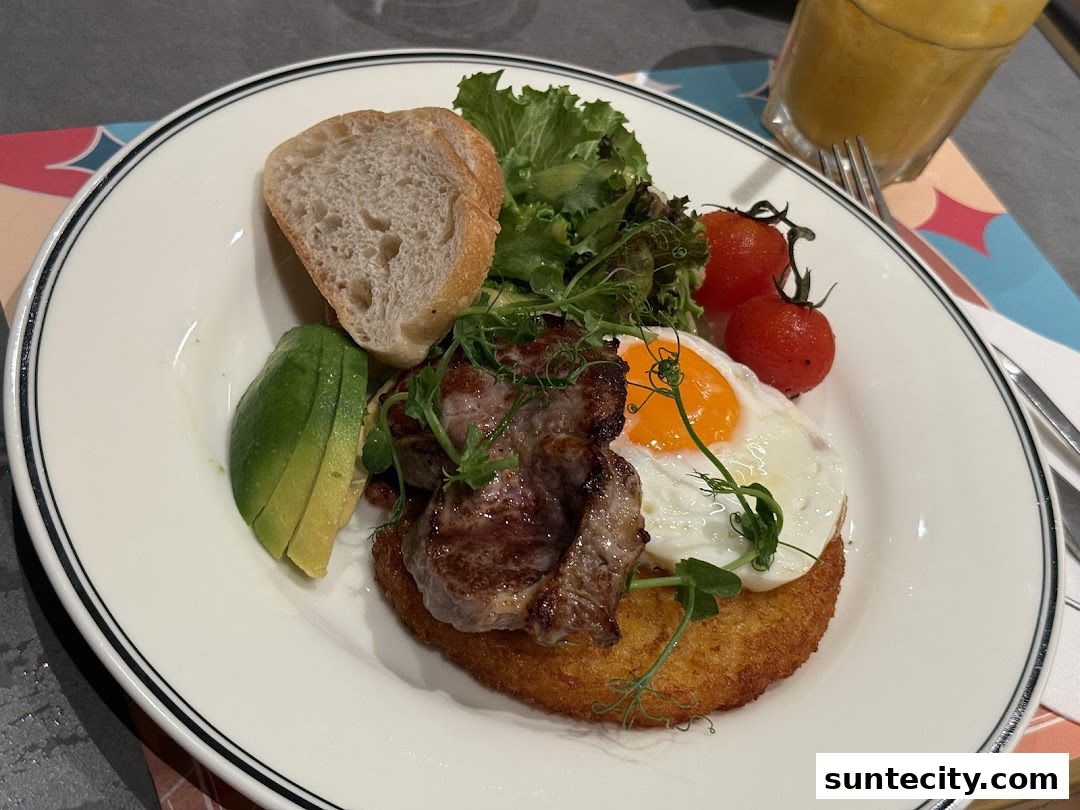A delicious breakfast plate with steak, fried egg, avocado, bread, and tomatoes.