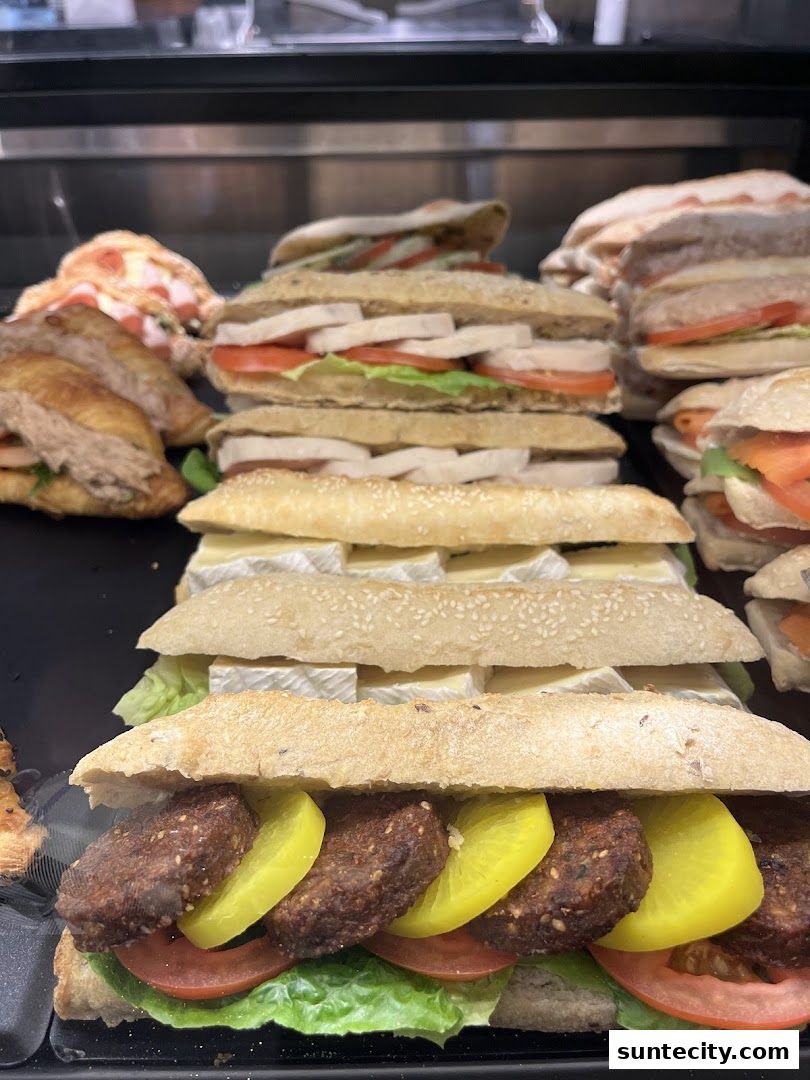 A close-up view of various freshly made sandwiches and pastries displayed in a refrigerated case.