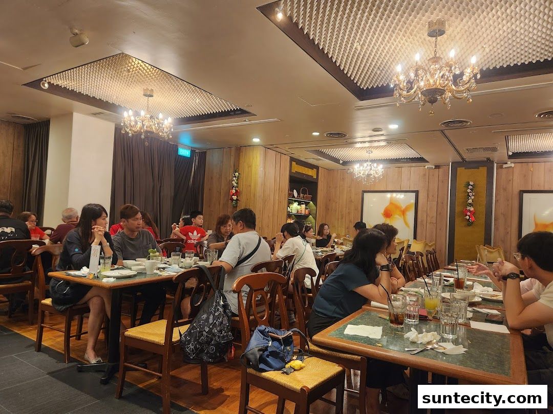 Diners are seated at tables in a restaurant with elegant chandeliers and wood-paneled walls.