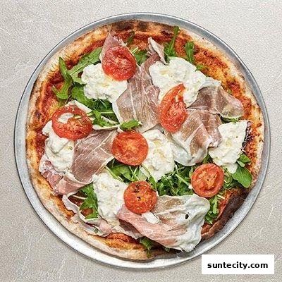 A delicious pizza topped with prosciutto, burrata cheese, cherry tomatoes, and arugula.