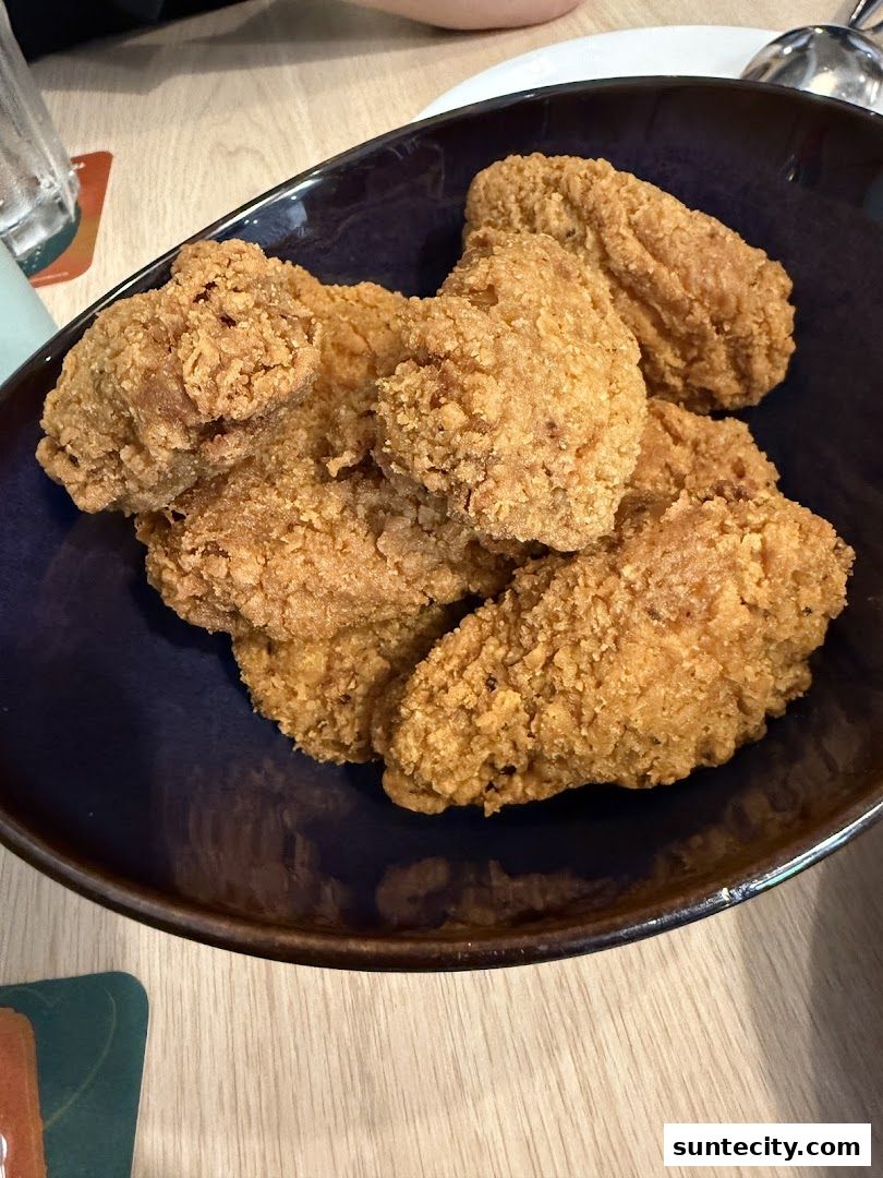 A close-up shot of crispy fried chicken wings served in a dark blue bowl.