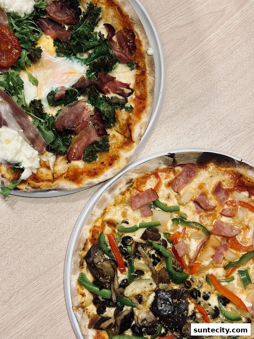 Two delicious pizzas, one with prosciutto, egg, and greens, the other with vegetables and ham.