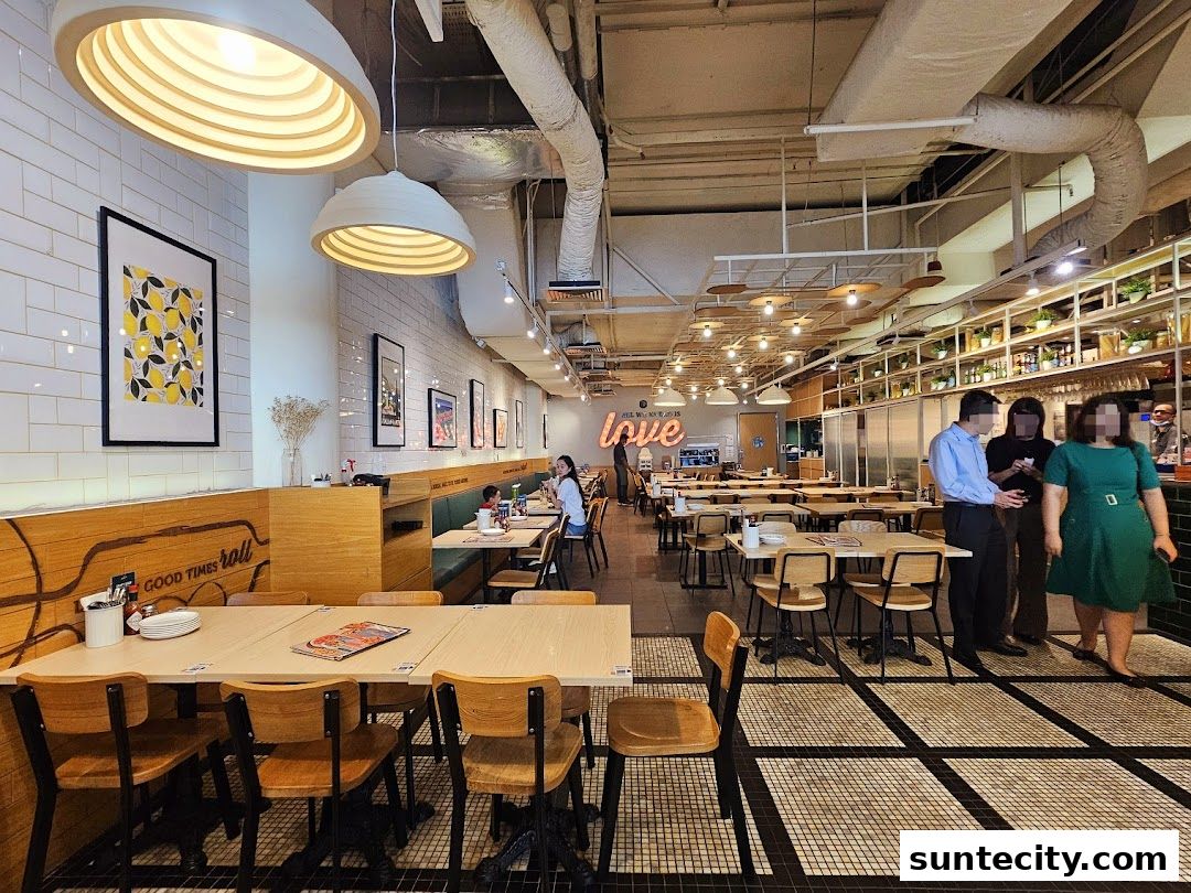 Interior view of a brightly lit restaurant with tables, chairs, and people dining.