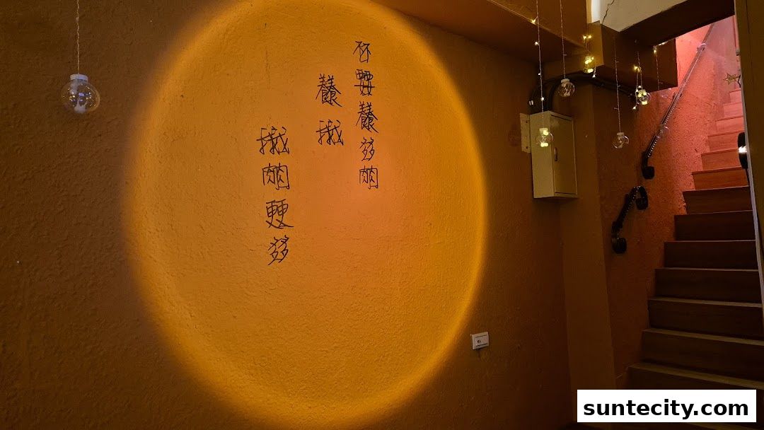 Interior shot of a shop with orange walls, calligraphy, and a staircase with string lights.