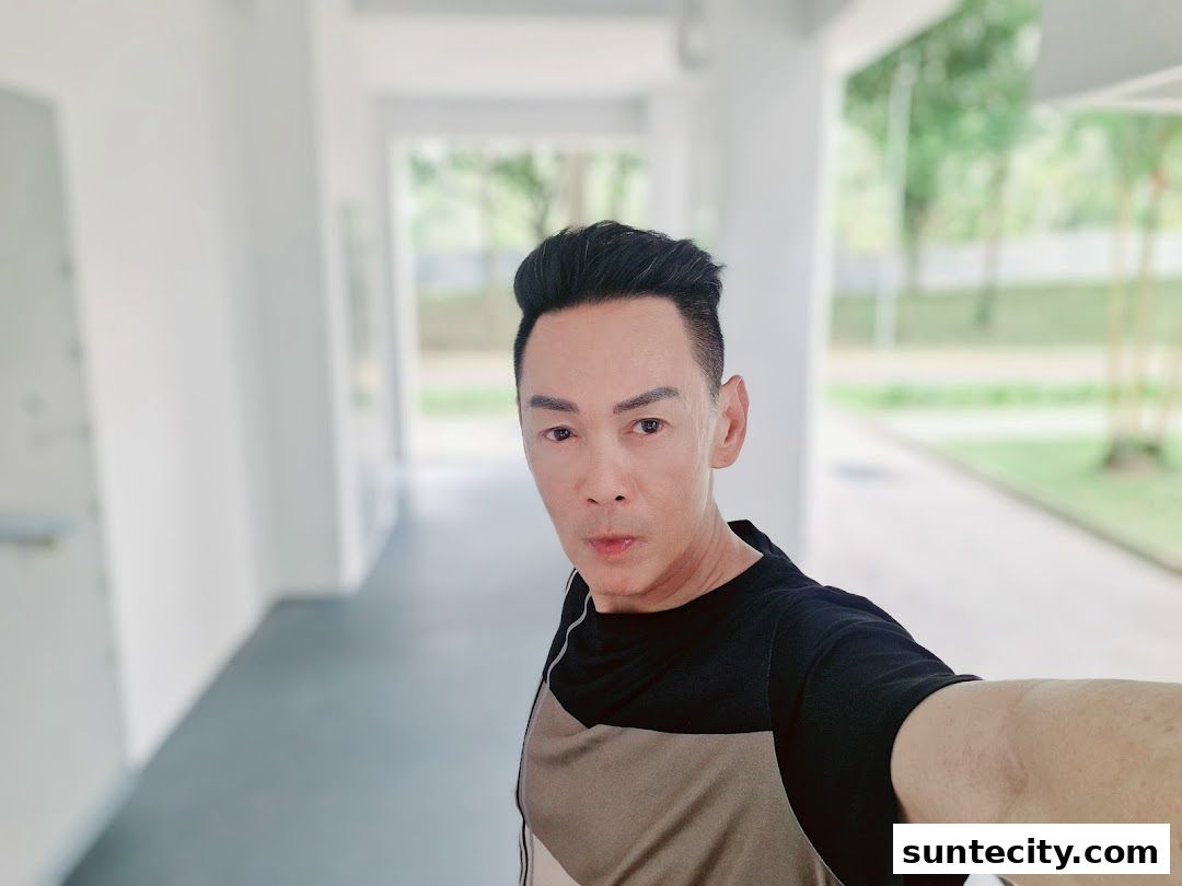 A man with styled hair takes a selfie in a bright, modern hallway.