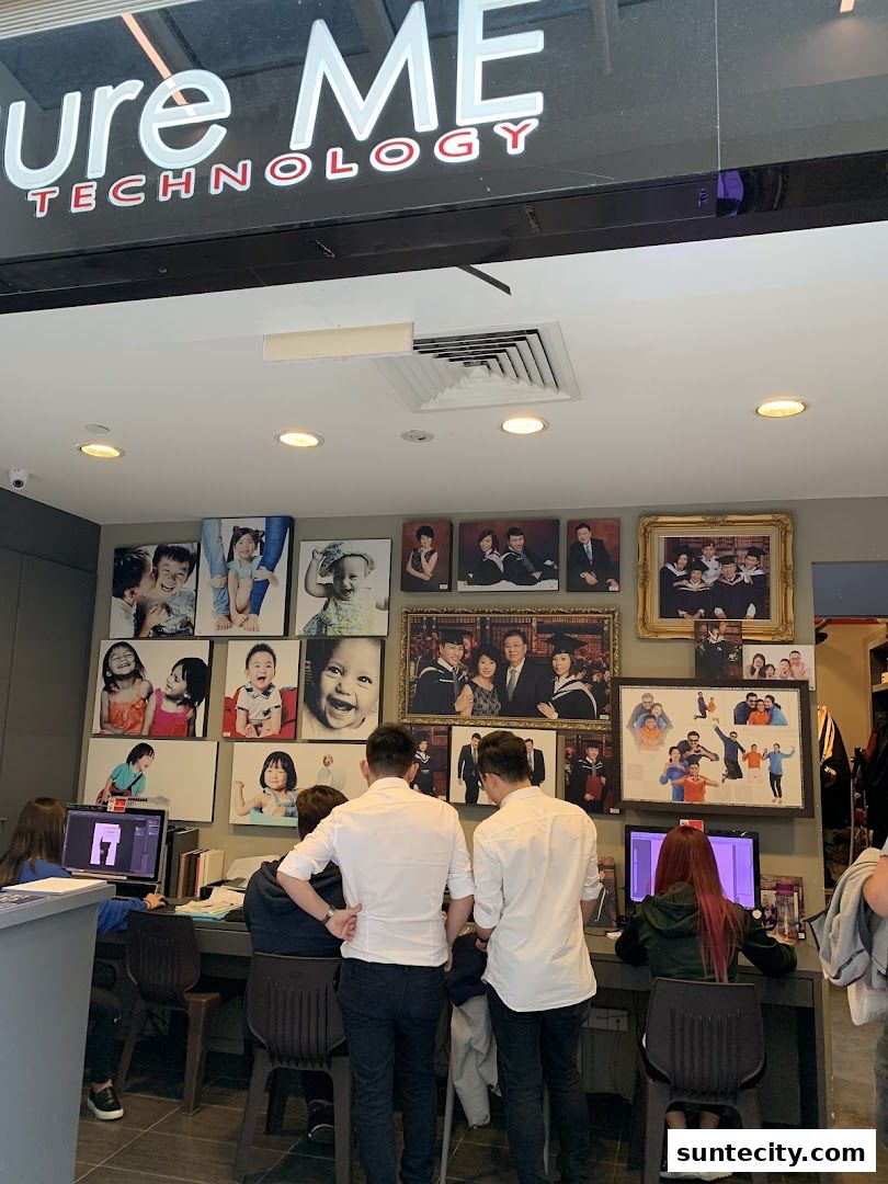 Shop interior with photos on the wall and people working at computers.