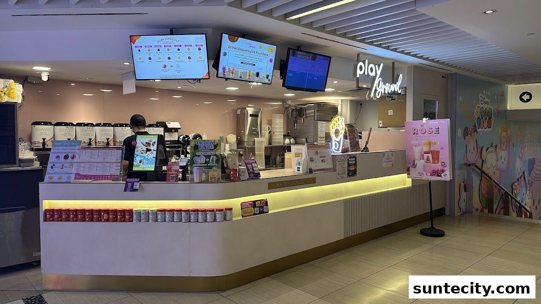 A boba tea shop counter with digital menus and various drink ingredients displayed.