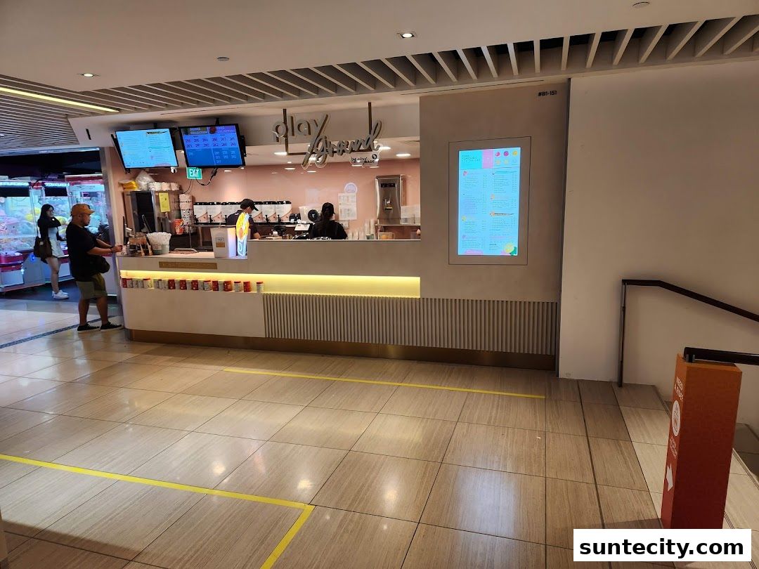 A brightly lit shop counter with staff serving customers and a digital menu displayed.