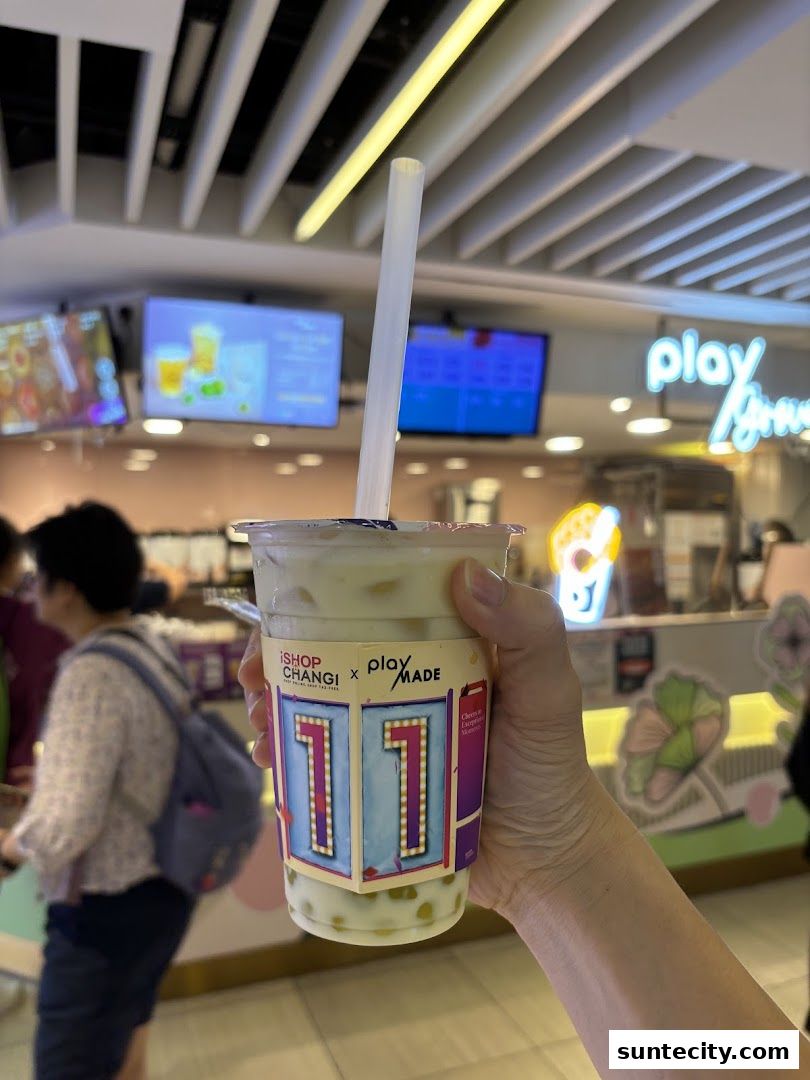 A hand holds a bubble tea with a special sleeve from Playground by PlayMade.