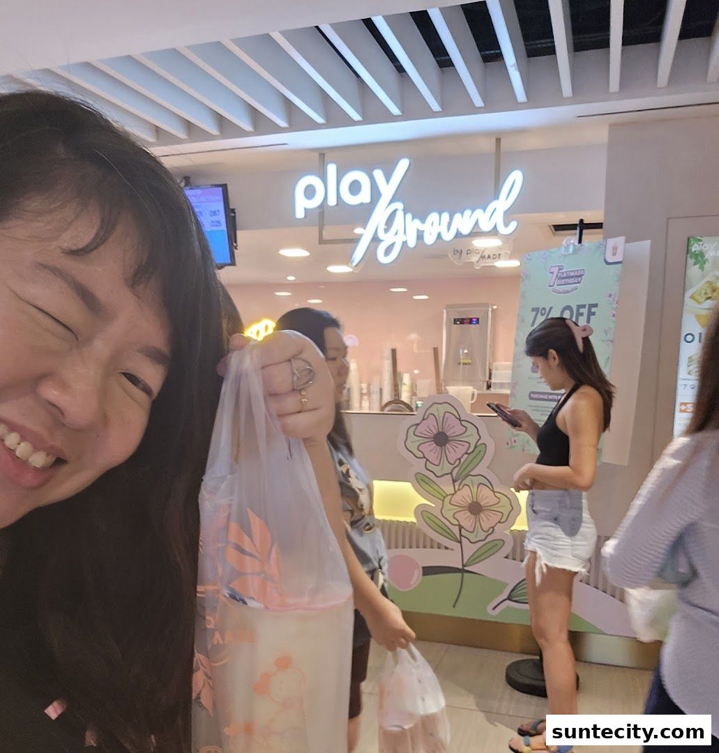People are queuing at a brightly lit shop with a neon sign that says 'playGround'.