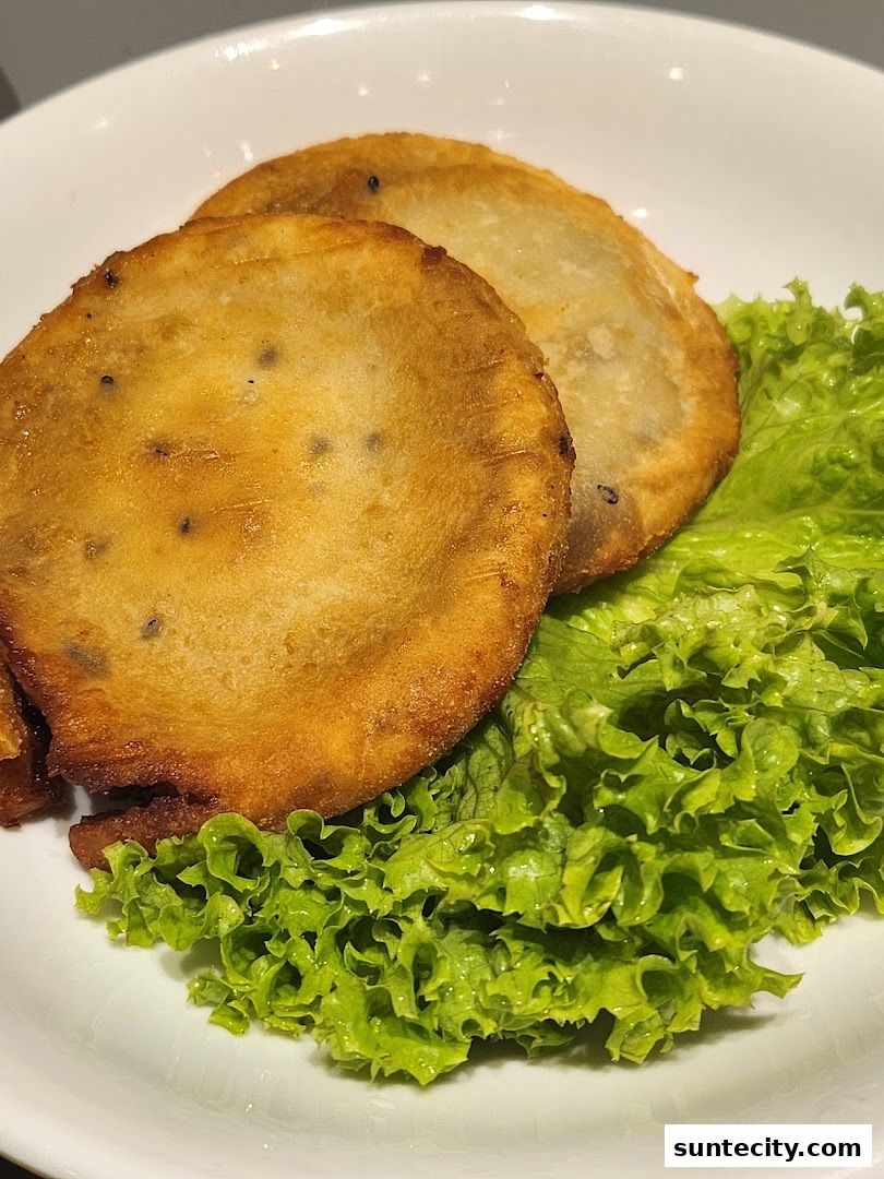 Close-up of two golden-brown Korean street food items served on a bed of fresh lettuce.