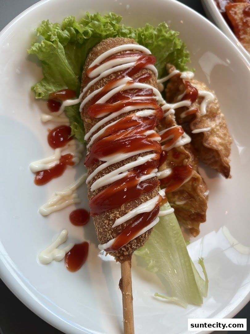 A delicious Korean corn dog drizzled with ketchup and mayonnaise, served with fried dumplings.