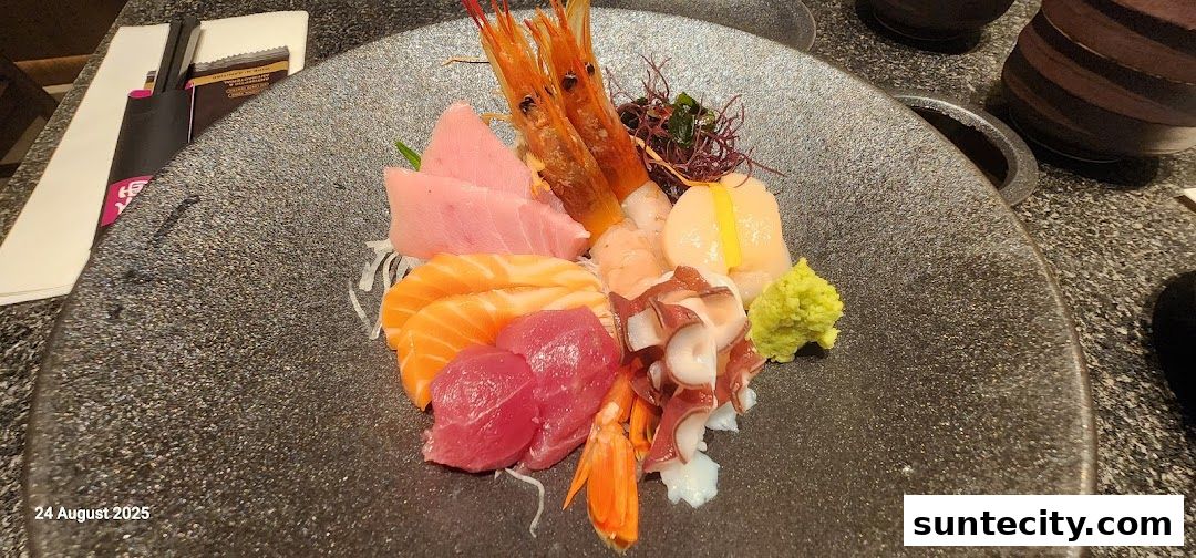 A platter of assorted sashimi, including tuna, salmon, shrimp, scallop, and octopus, served with wasabi.