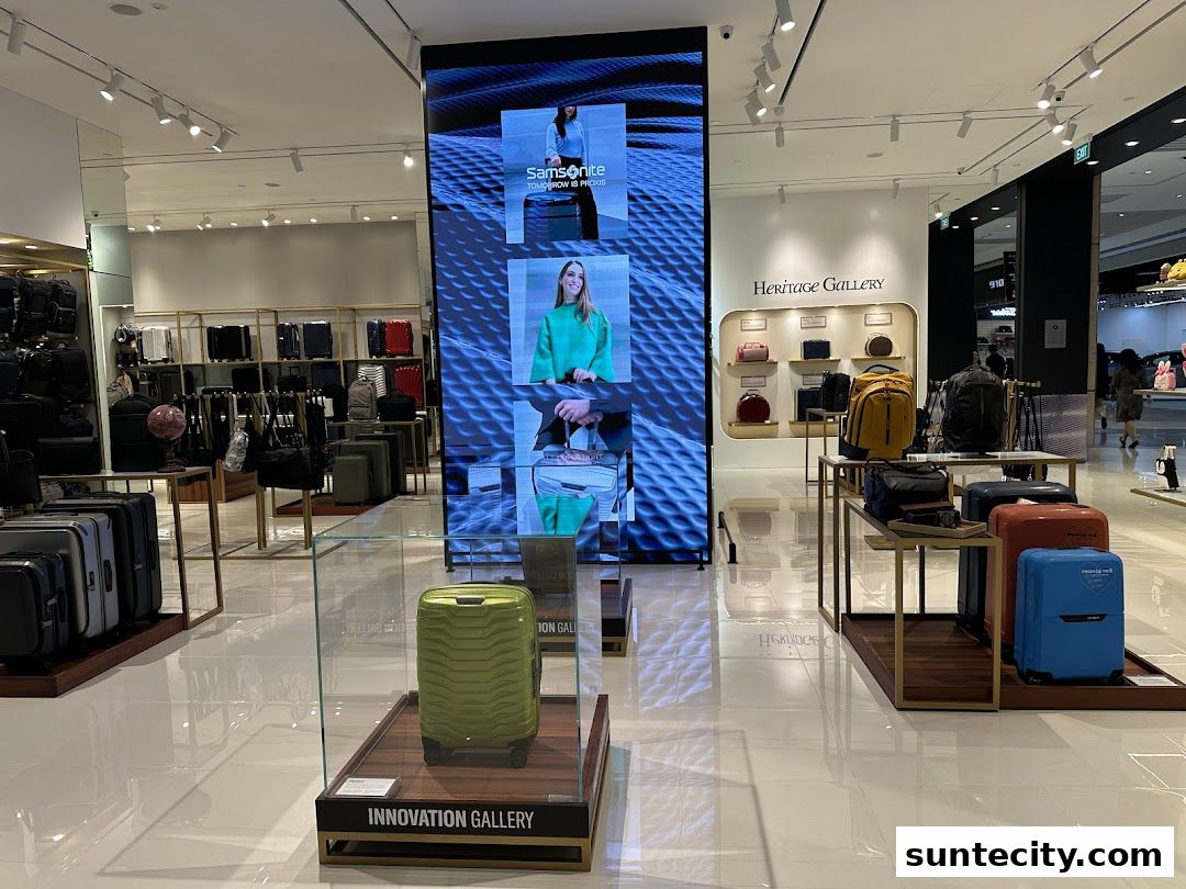 Interior of a Samsonite store showcasing various luggage and bags, with a large digital display.