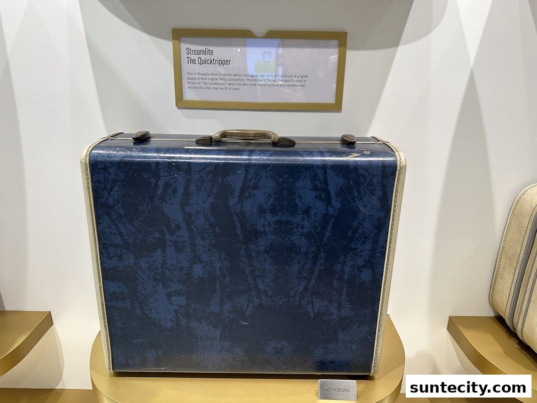 A vintage blue Samsonite suitcase on display with a descriptive plaque.