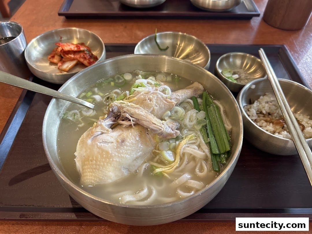 A hearty bowl of Korean chicken noodle soup with kimchi and rice.