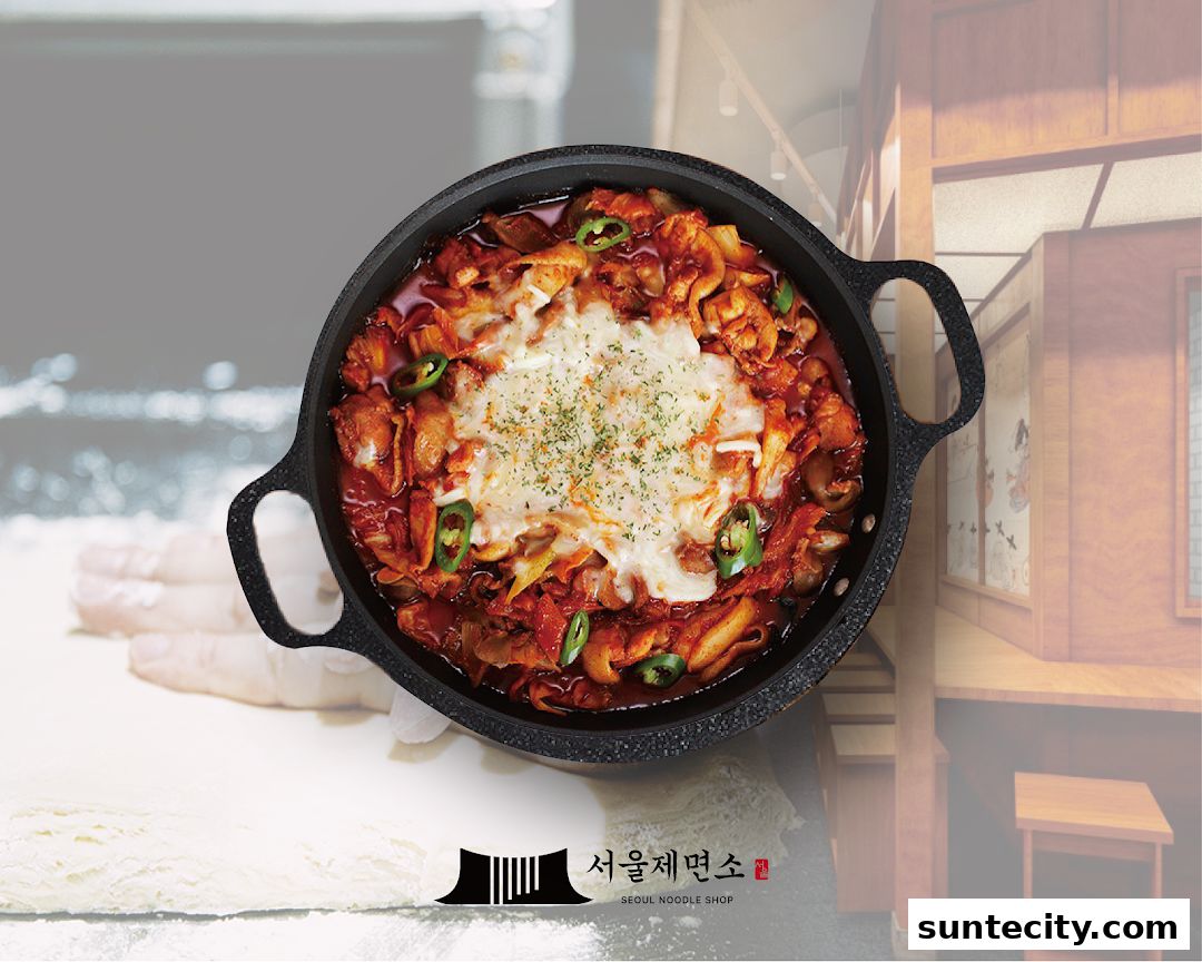 A close-up of a delicious Korean dish with melted cheese and chili peppers in a black pan.