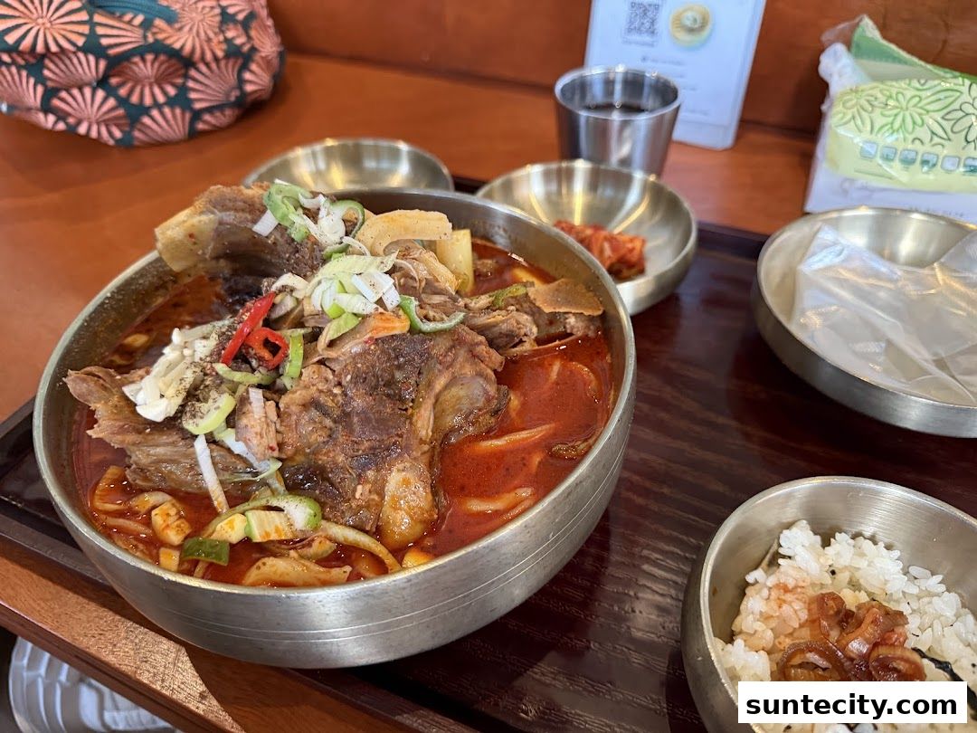 A hearty bowl of Korean stew with meat and vegetables, served with rice and kimchi.