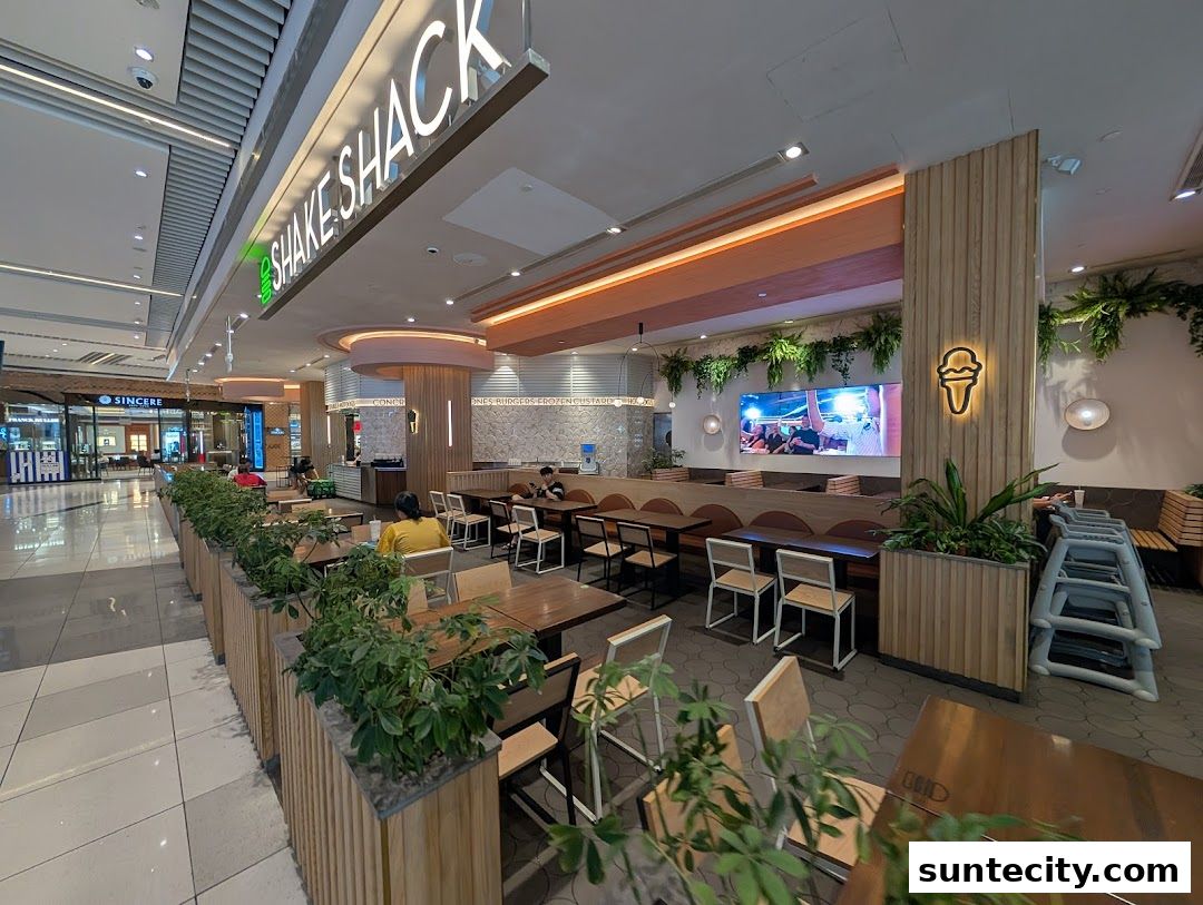 Interior view of Shake Shack Suntec with seating, plants, and a large screen.