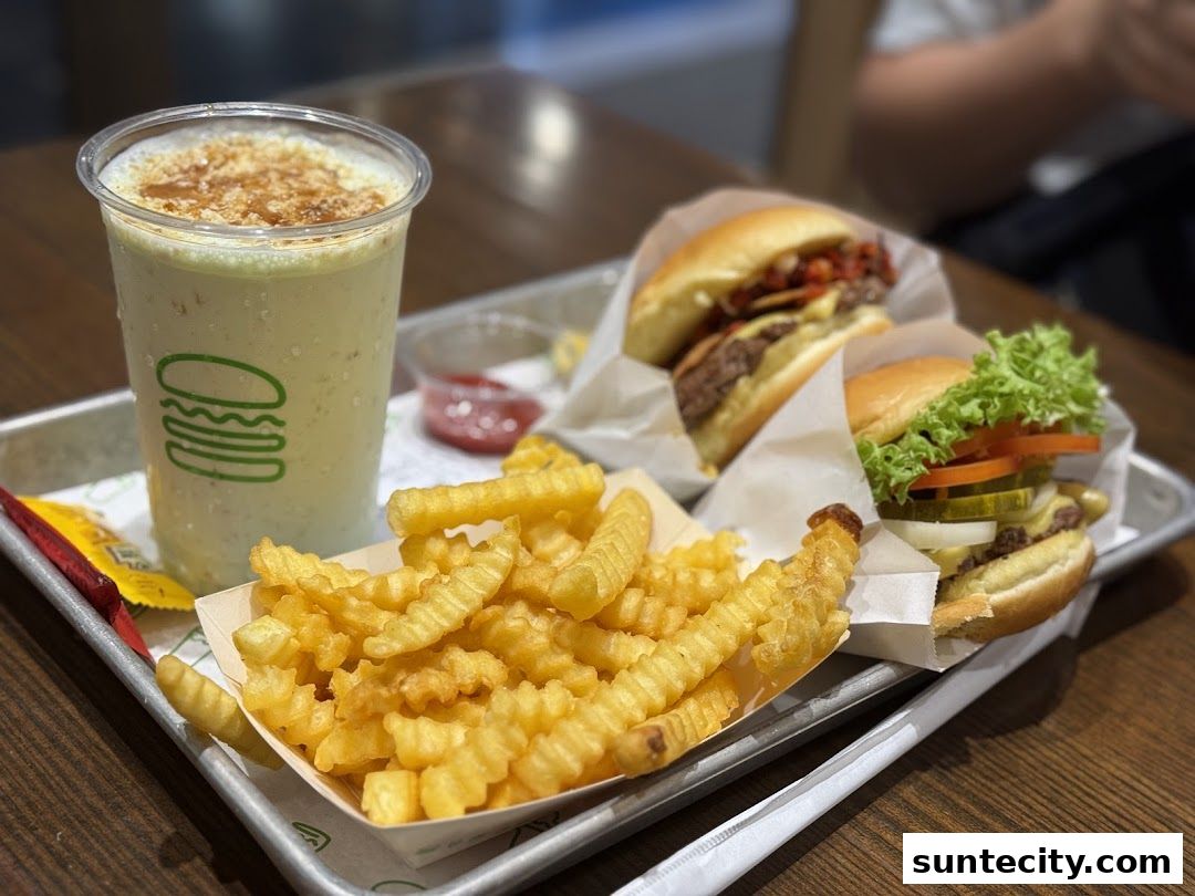 A tray of Shake Shack food including burgers, crinkle-cut fries, and a milkshake.