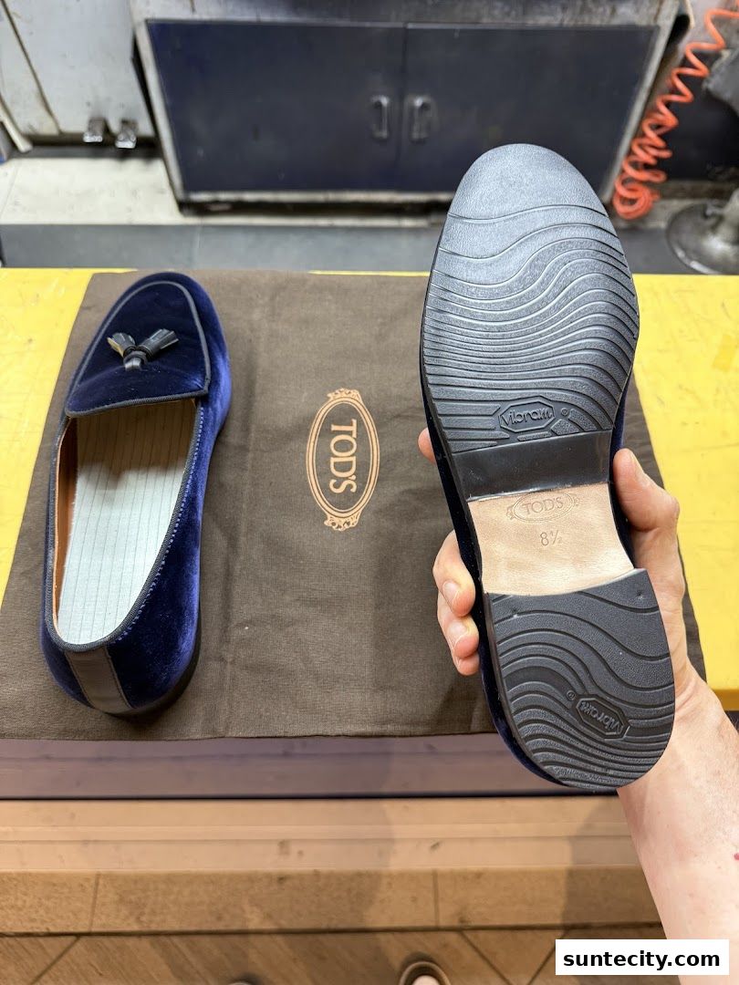 A pair of blue velvet loafers with tassels and a Vibram sole are displayed.