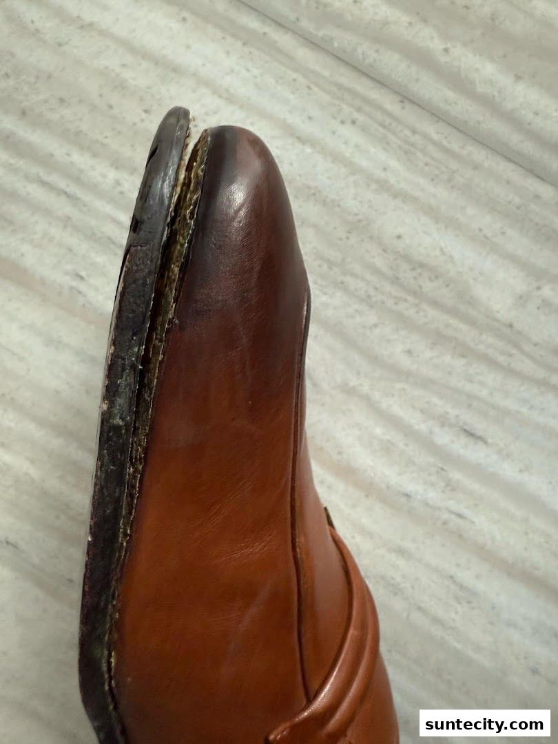 A close-up of a brown leather shoe with a detached sole.