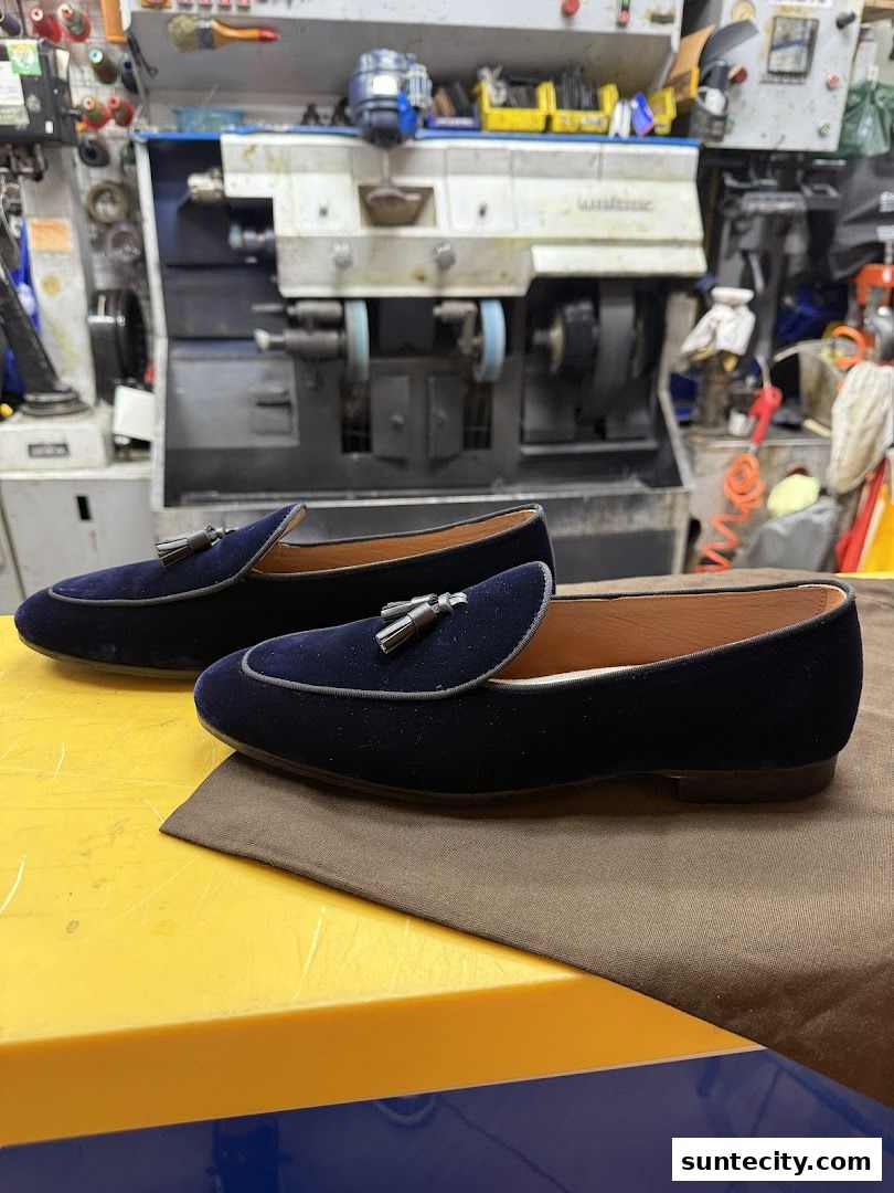 A pair of elegant navy velvet loafers with tassels displayed in a workshop.