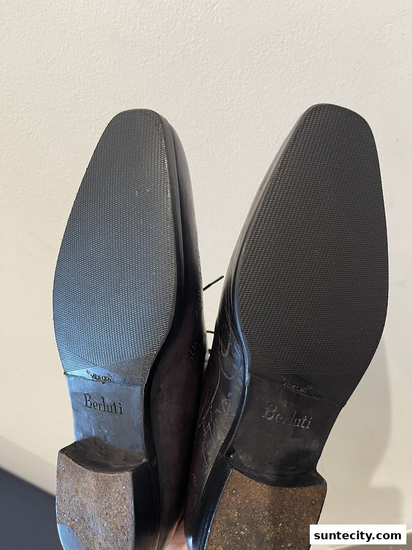 Close-up view of the soles of two Berluti leather shoes, showcasing their craftsmanship.