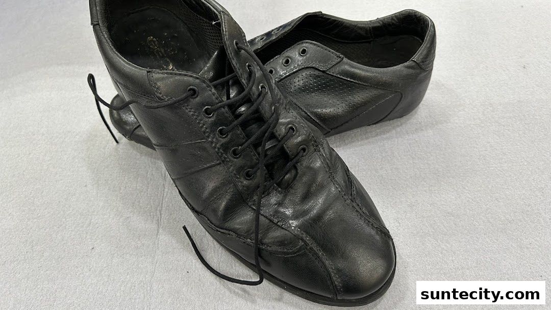 A pair of black leather lace-up shoes with perforated detailing.