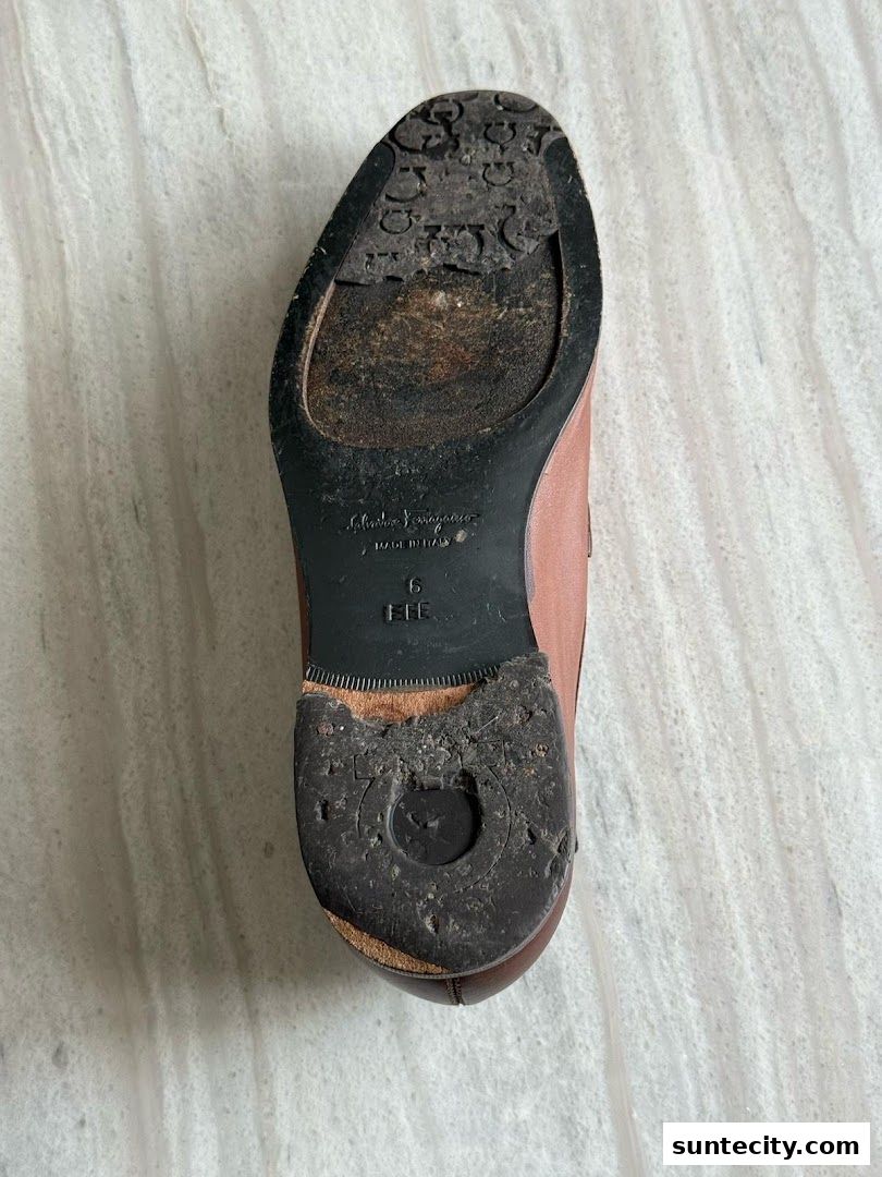 The worn sole of a brown leather shoe with visible branding and signs of wear.