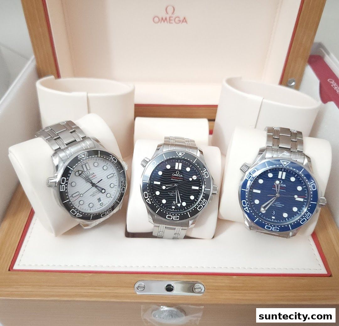 Three Omega watches displayed in a wooden box, showcasing different dial colors.