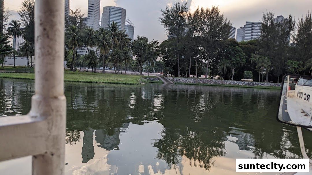 View of a calm body of water with reflections of buildings and trees, from a boat.