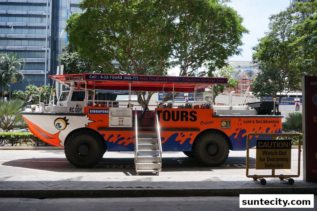 A bright orange amphibious bus, branded as Singapore DUCKtours, is parked on a street.